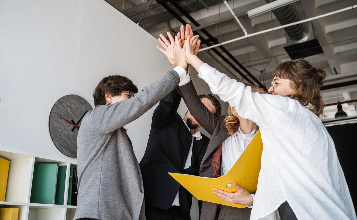 Cheerful young group of people standing in the office and giving high five