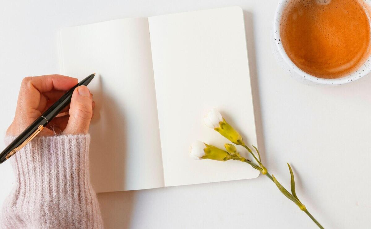 Woman writing on blank notebook with pen over white background