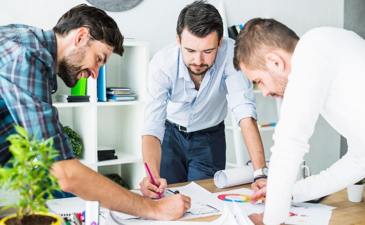 Group of male architect planning blueprint over wooden desk