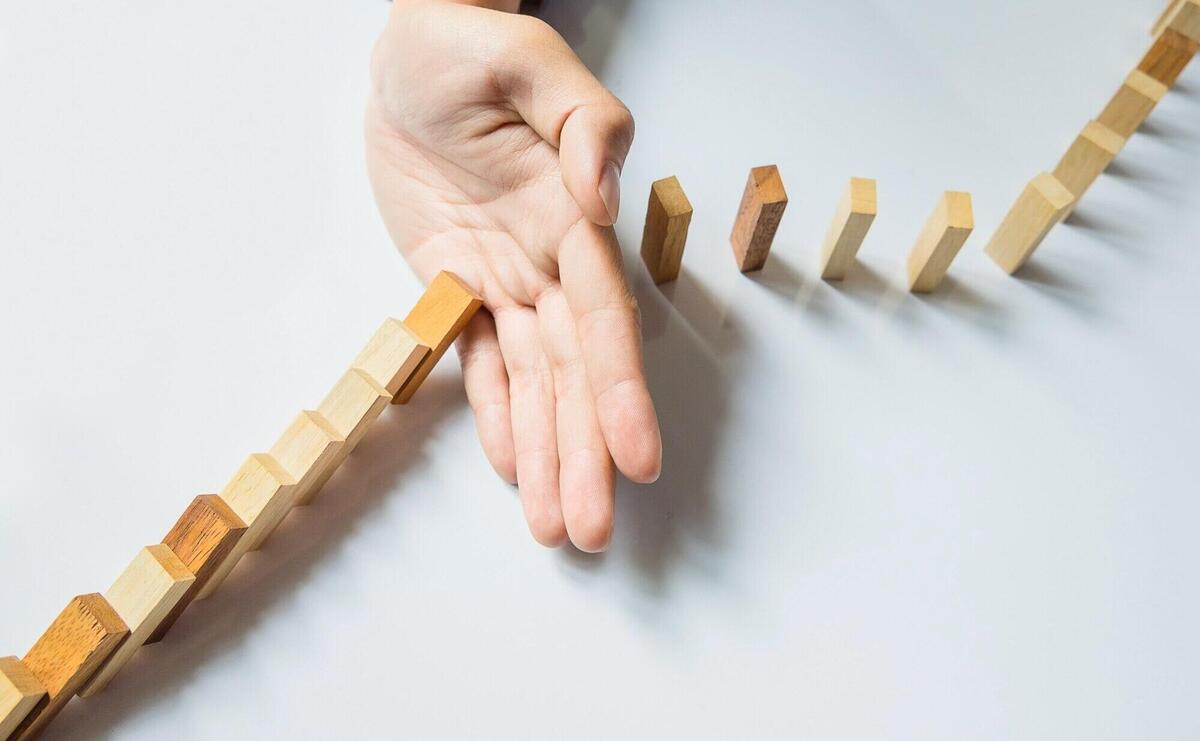 Businessman hand stop dominoes continuous toppled or risk with copyspace