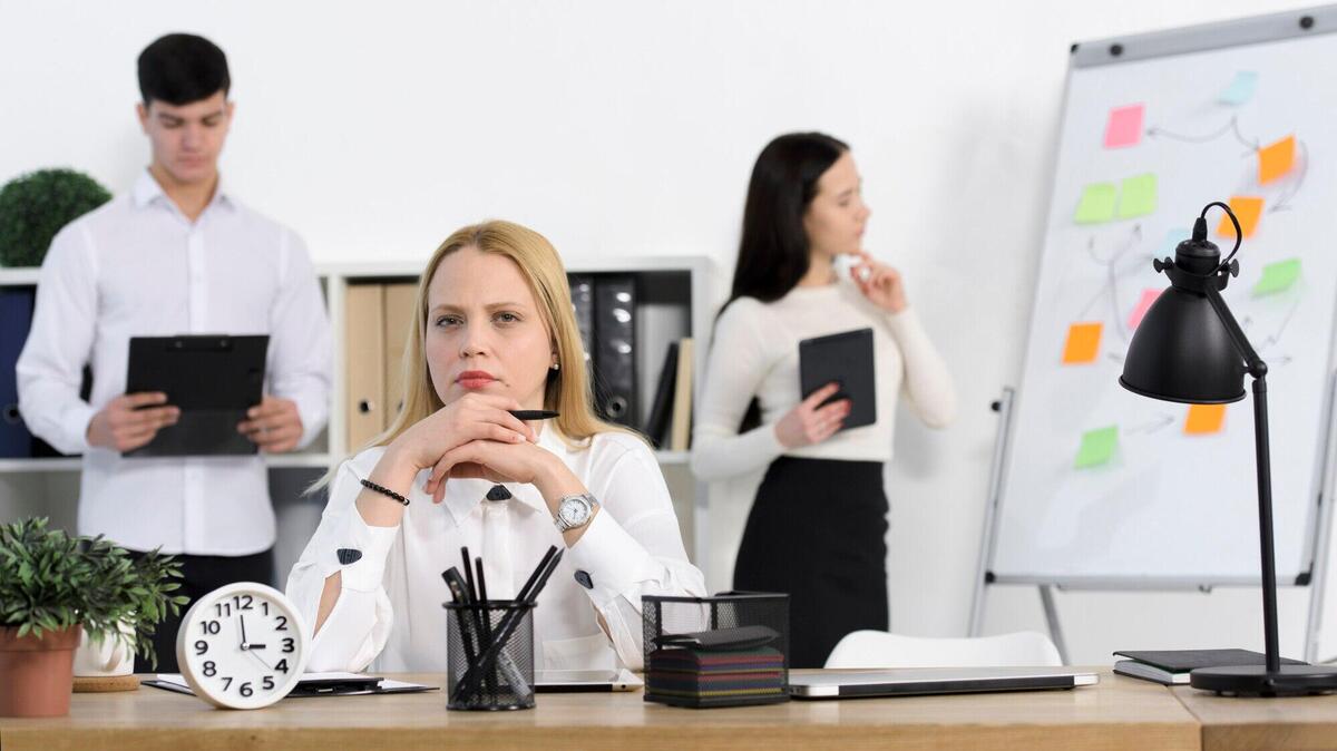 Colleague standing behind the serious young businesswoman at workplace