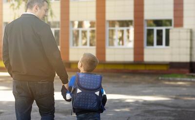 Father and kid on first school day back view