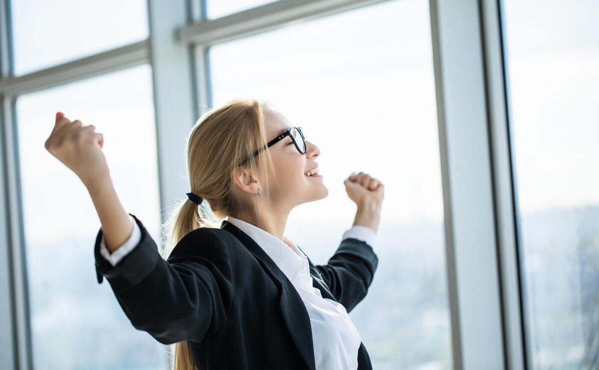 Business woman excited hold hands up raised arms celebrate victory in modern office