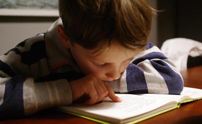 A child is reading from a book.