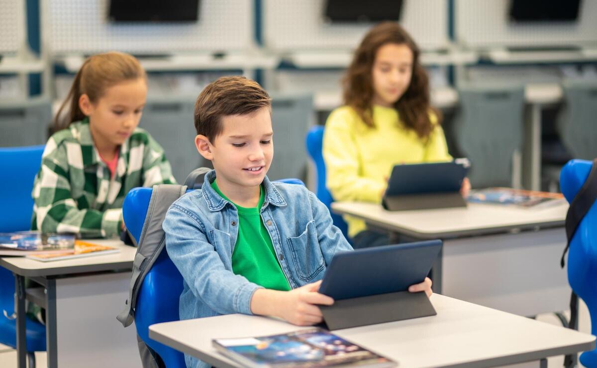 Boy and girls sitting at desk looking at tablet