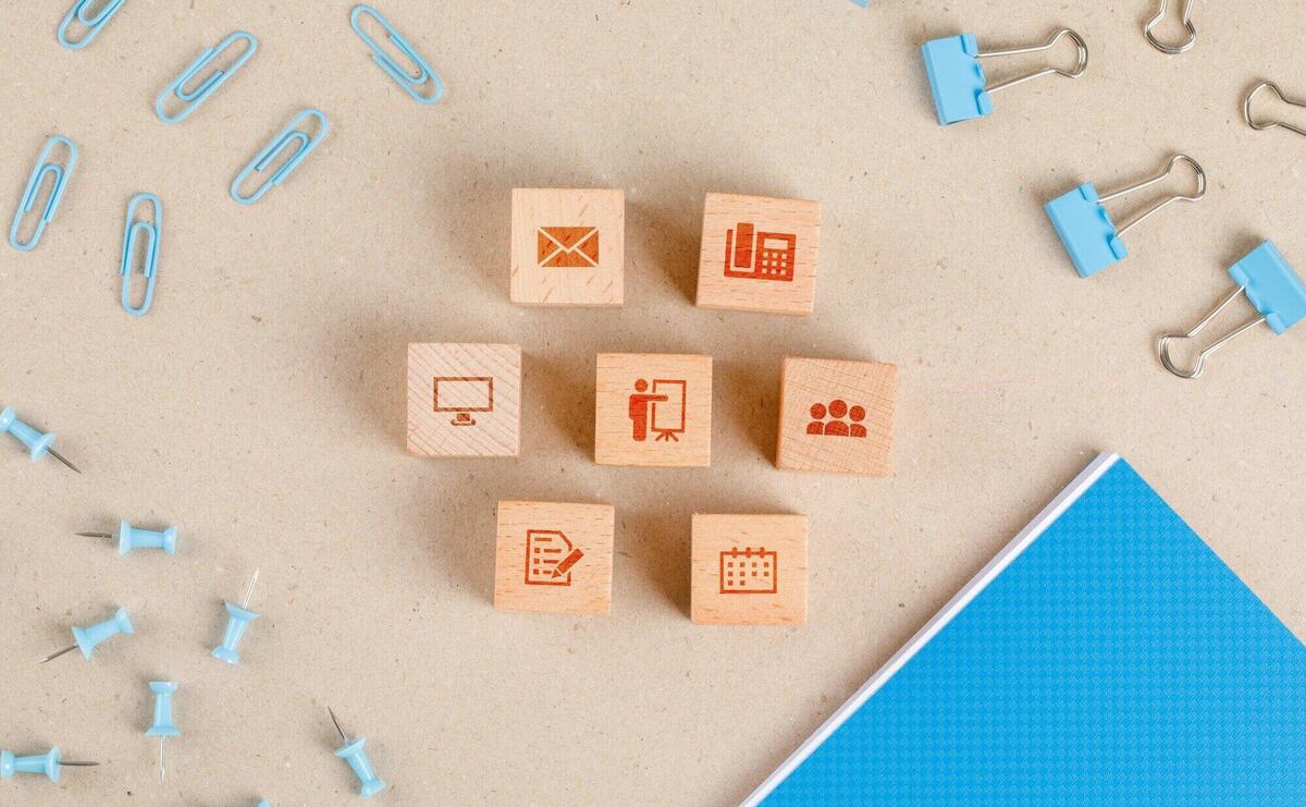 Office supplies concept with icons on wooden cubes, stationery set flat lay.