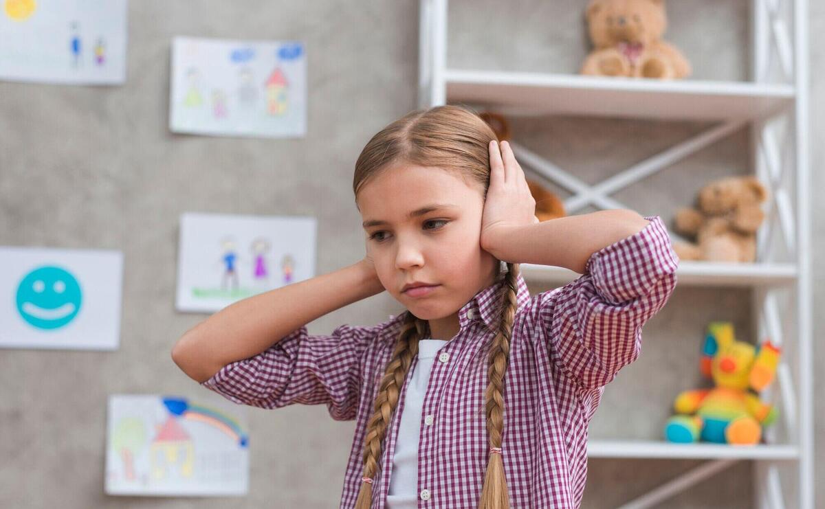 Portrait of sad girl covering her ears with two hands