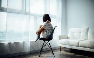 Woman sitting on the chair and looking towards the window.