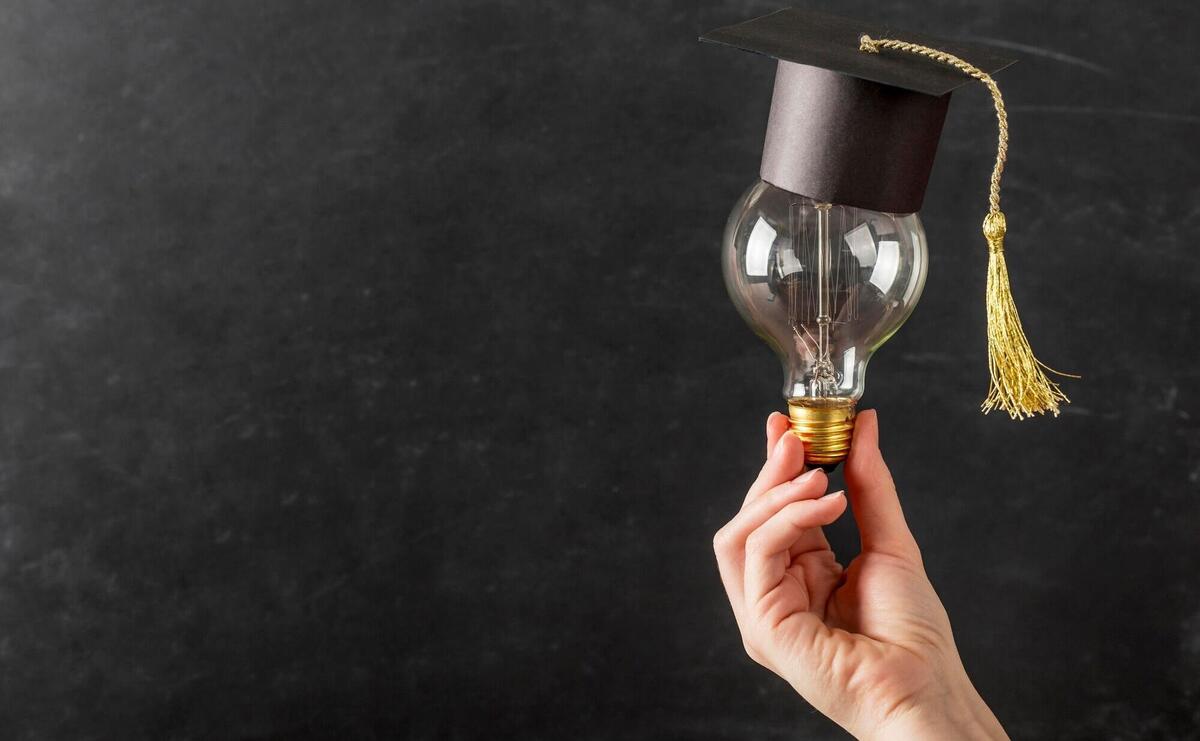 Person holding a light bulb with graduation cap