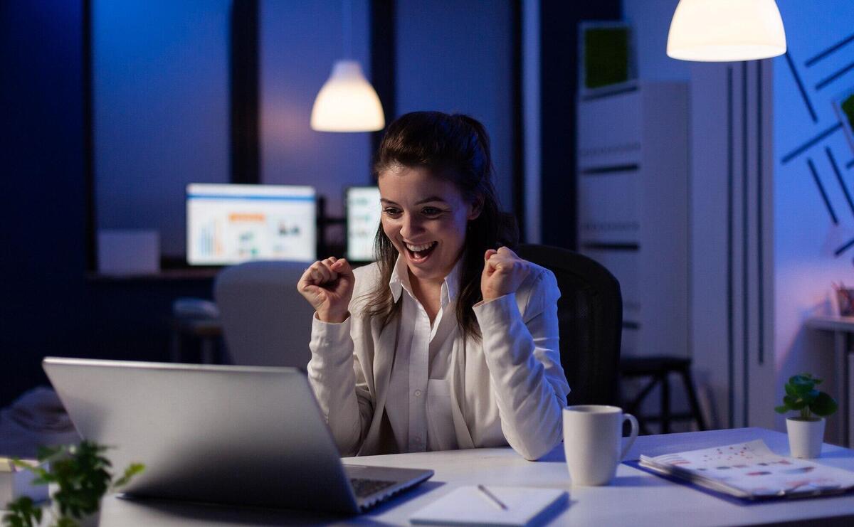 Happy businesswoman reading great online news on laptop working on economic opportunity at start up company office