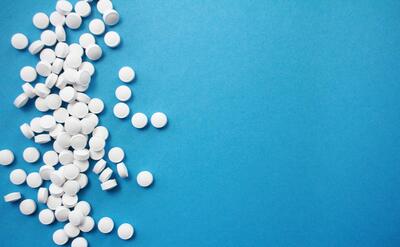 White medicine pills on blue background.