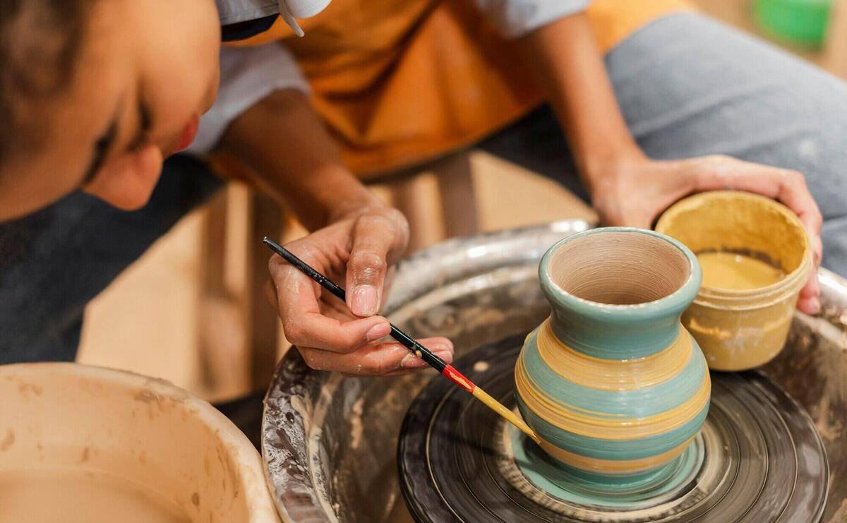 Close up woman painting clay pot