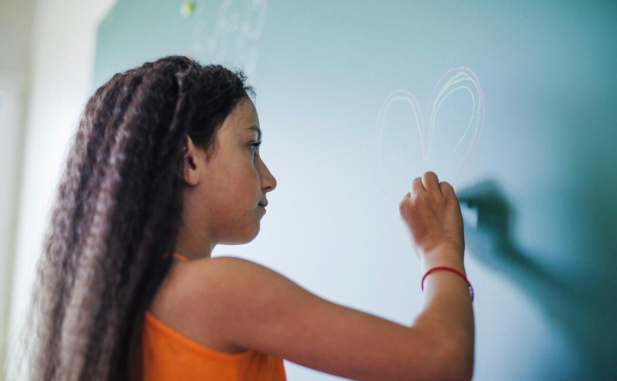 Girl drawing heart on chalkboard