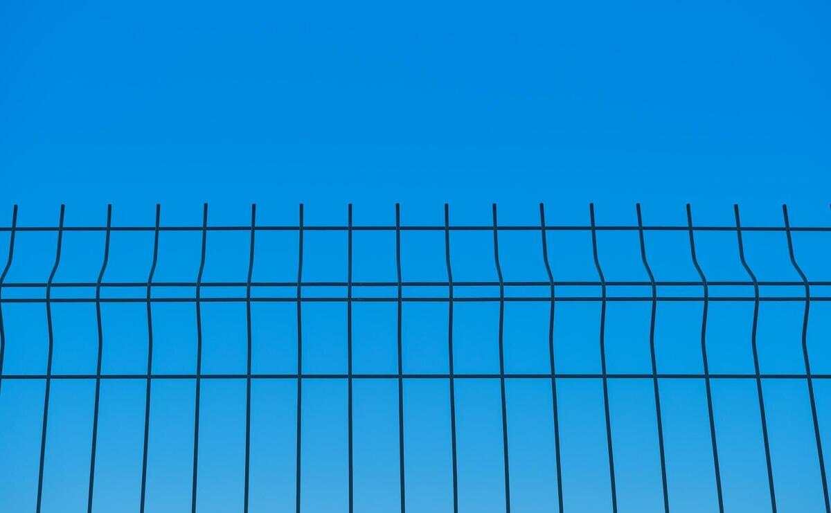 Metal fence against the background of a blue boundless sky a blurred background the idea of freedom and the removal of restrictions a background for a poster or postcard