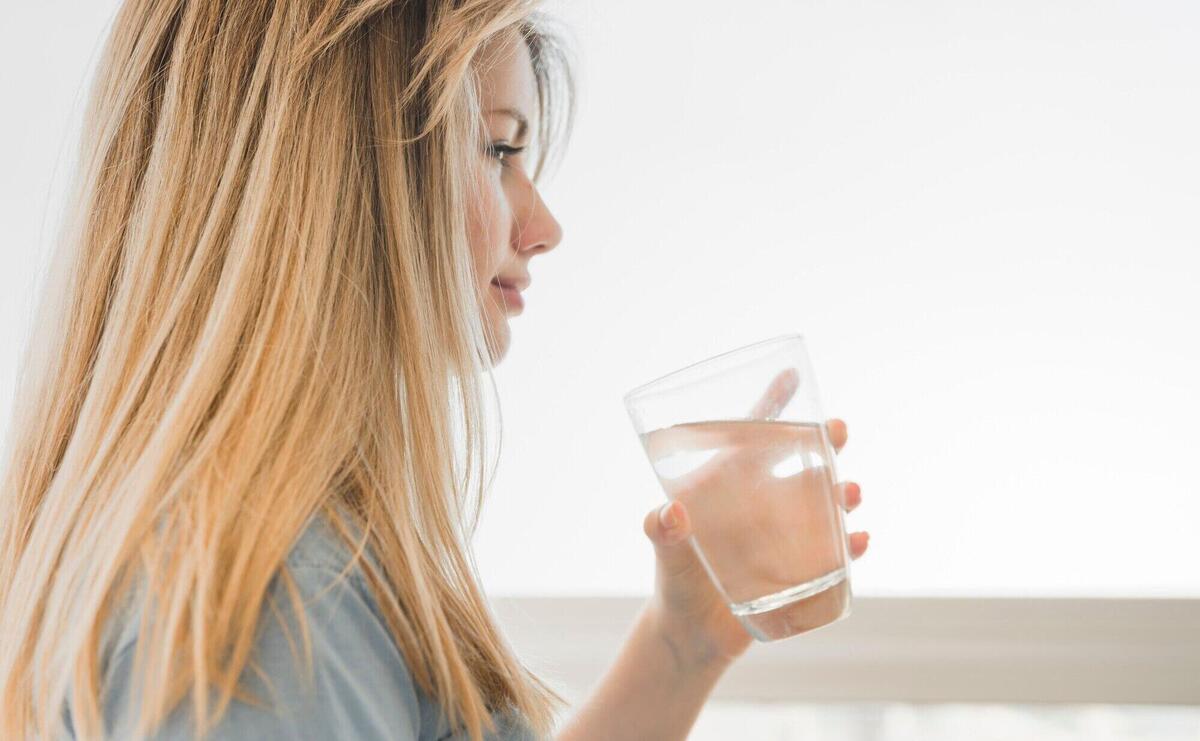 Blonde girl holding glass of water