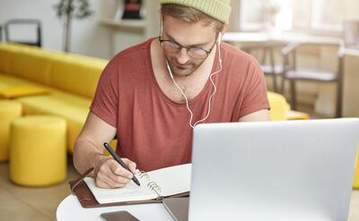 Young man sitting in cafe with laptop