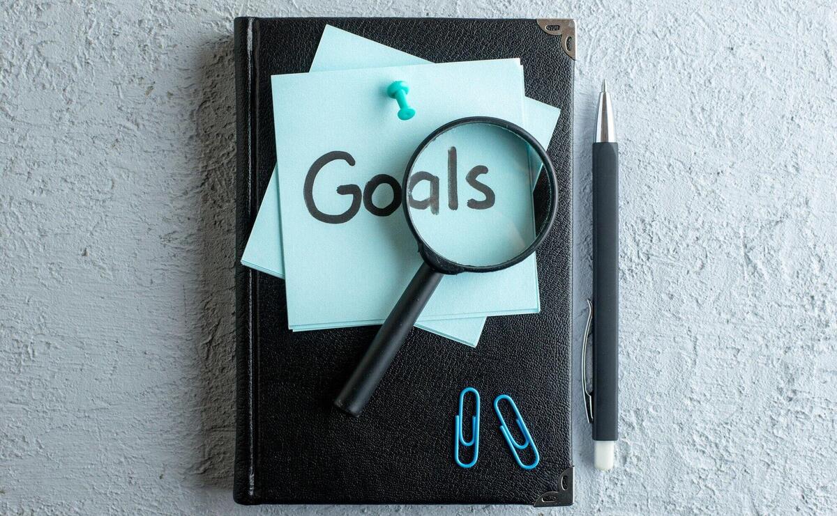 Top view goals written note with notepad and pen on white surface job office school copybook color college business