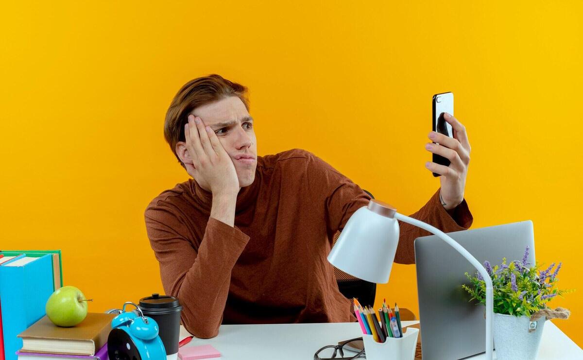 Confused young student boy sitting at desk