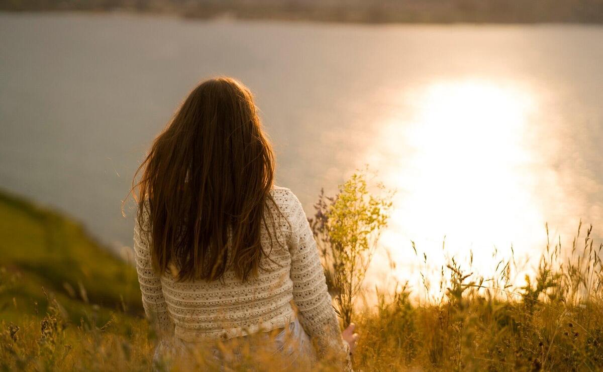 Back view woman sitting by the lake