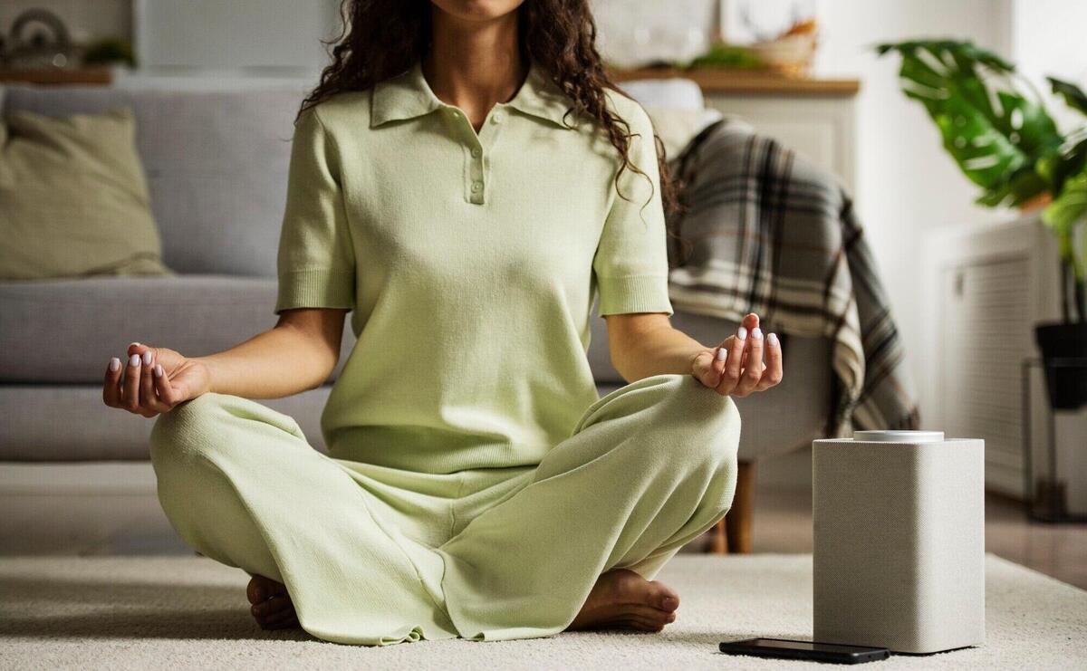 Front view woman meditating with smart speaker