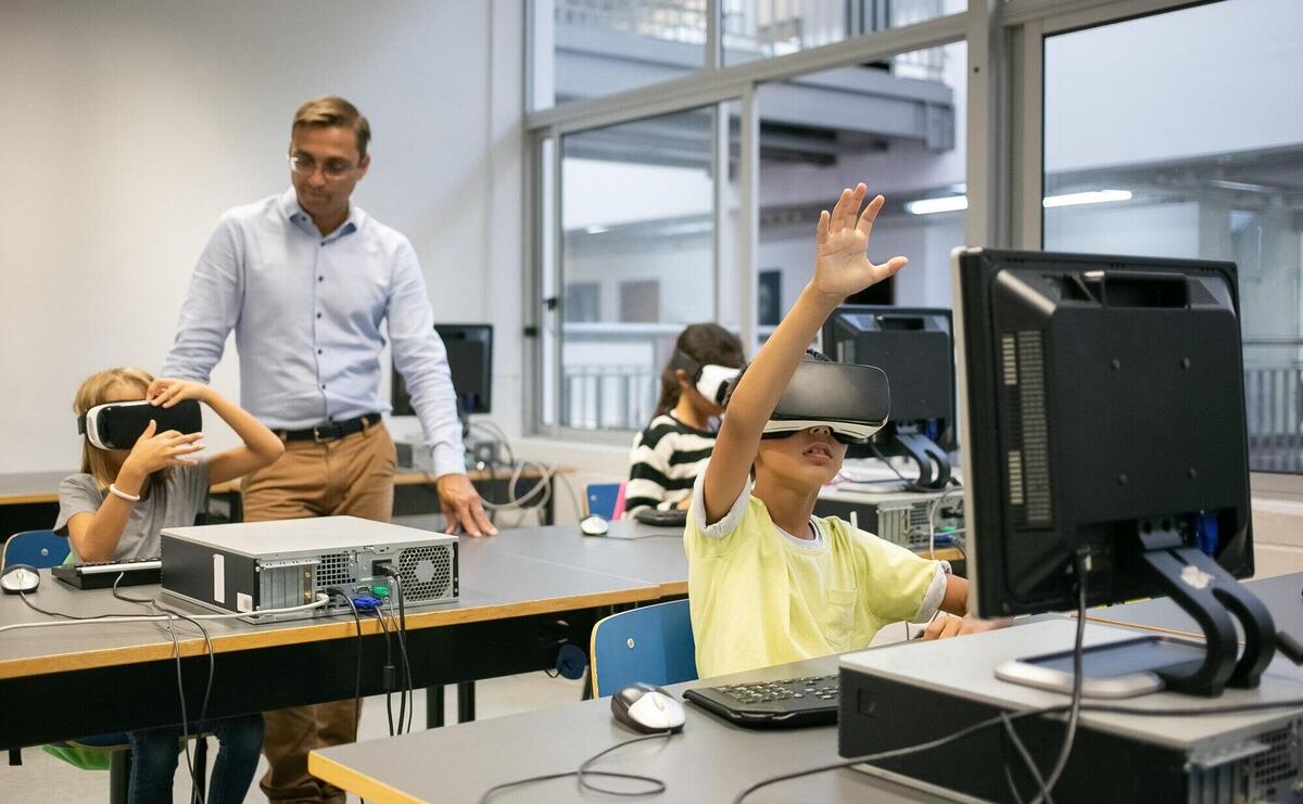 Group of multiethnic kids wearing VR headsets and teacher watching them