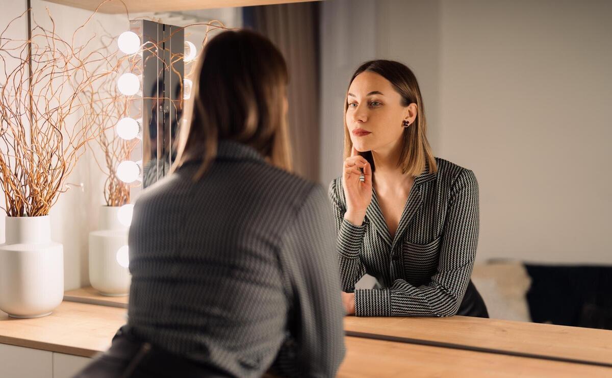 Selfconfident woman looking at her reflection into the mirror indoors beautiful interior design