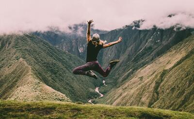 A woman is jumping on a mountain.